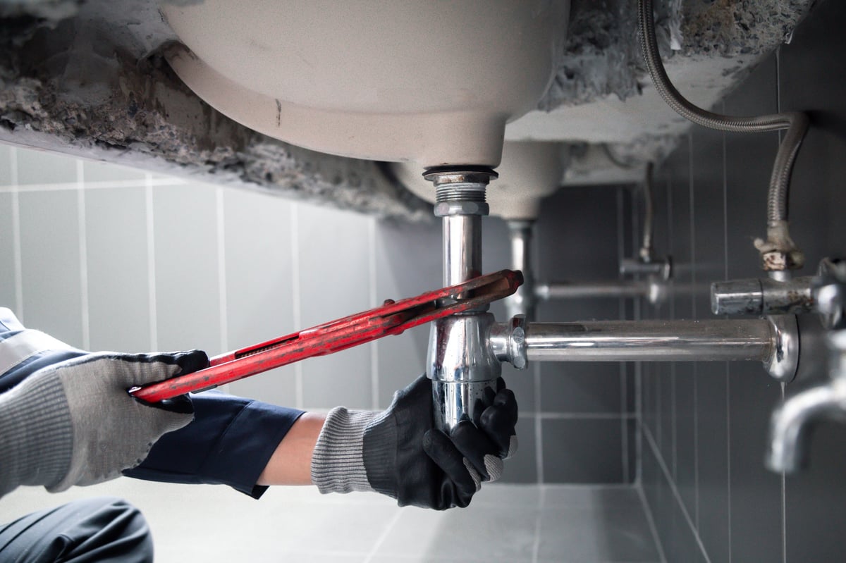 Professional plumber repairing water pipe
